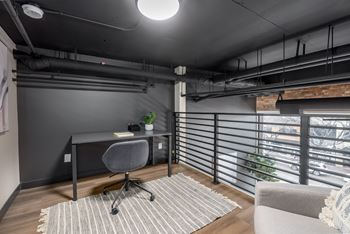 A modern home office with a desk, chair, and a window with blinds.